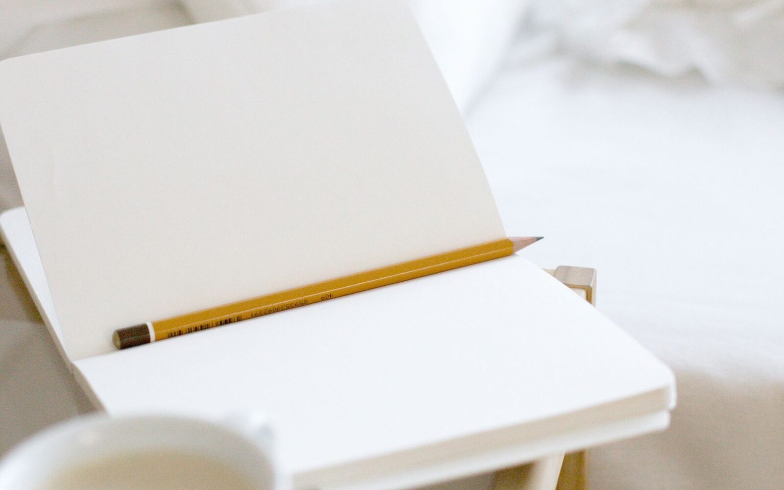 Carnet ouvert et crayon posés sur une table de chevet